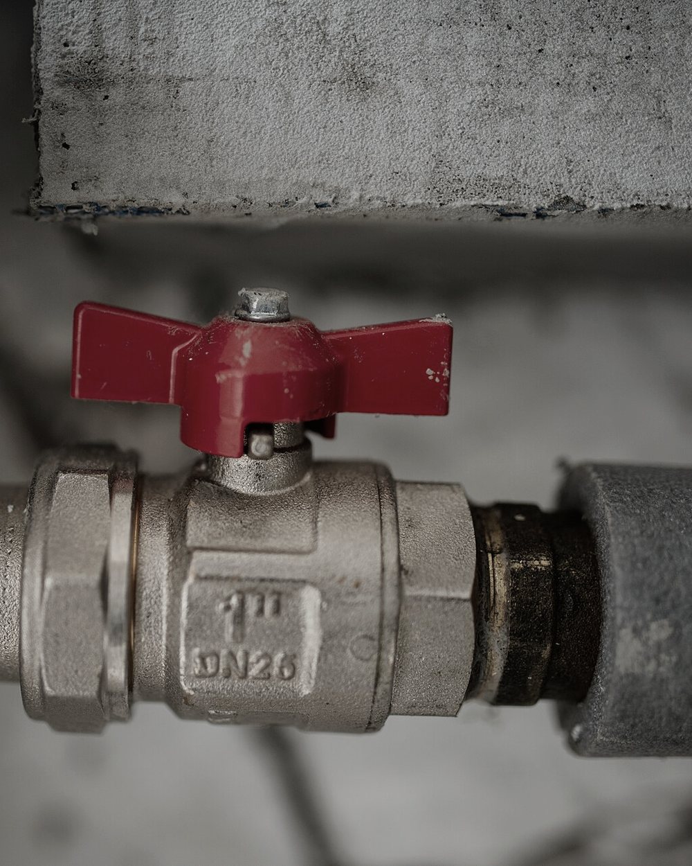 A brass ball valve with a red handle on a copper line.