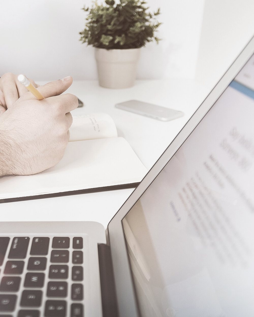 A rep takes notes beside a laptop open to an email.