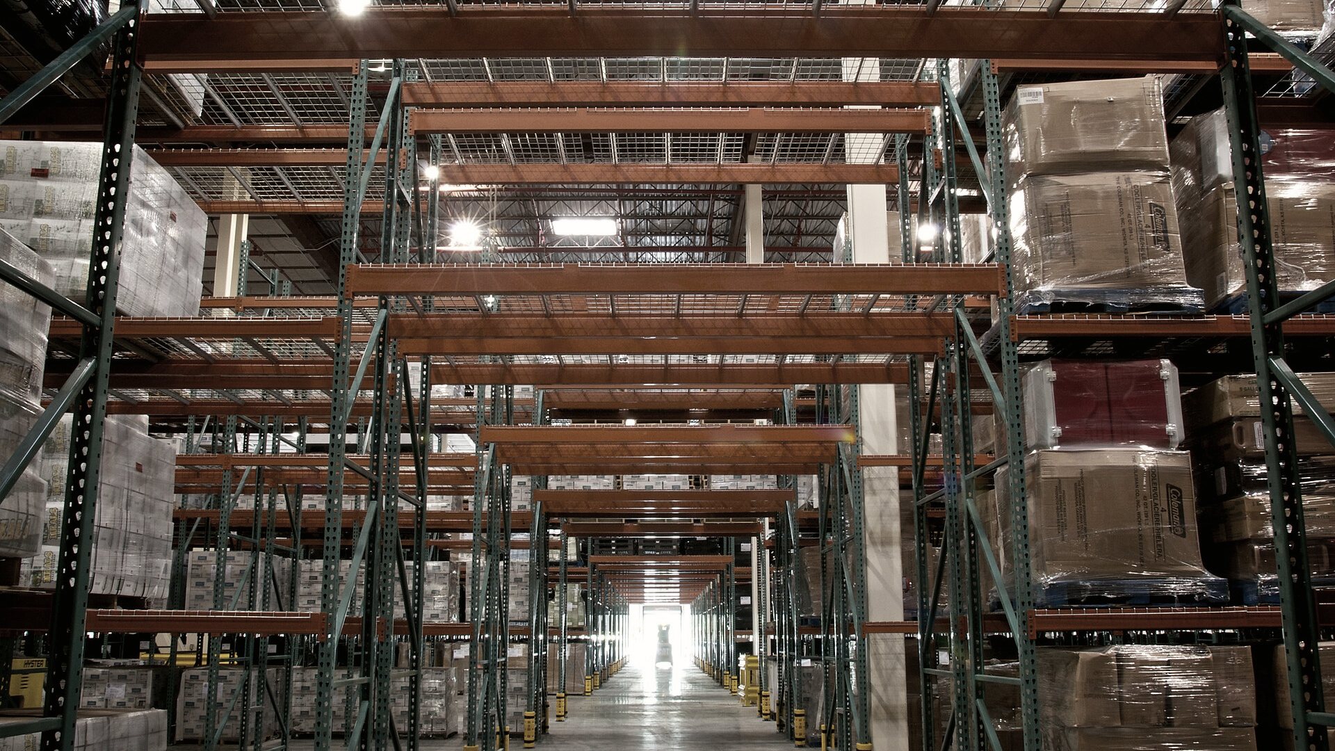 A long aisle of stocked pallet racking in a distribution center.